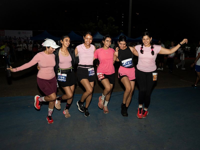 Five runners in pink link arms in the early morning.