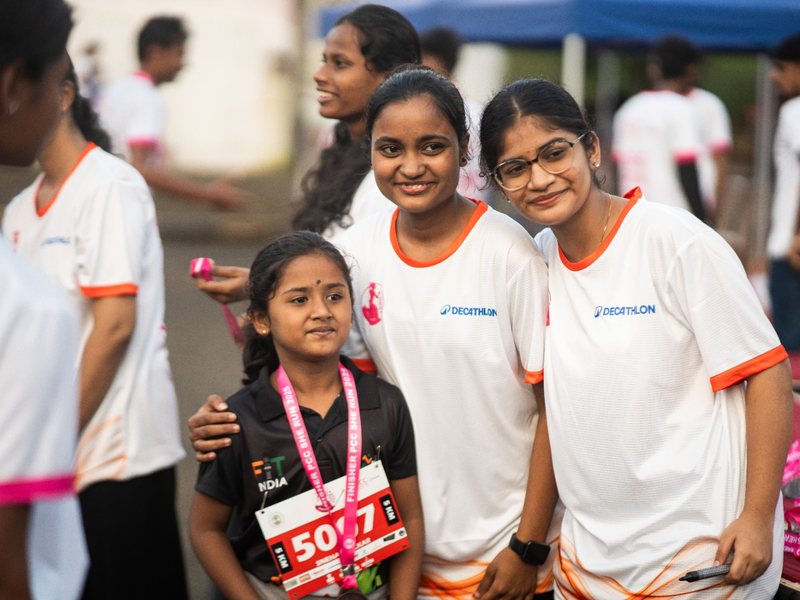 Volunteers with a young finisher holding her medal.